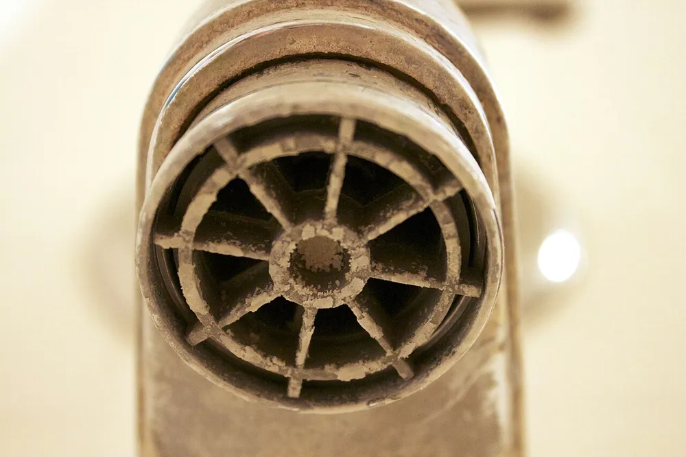 Close-up of a tub faucet aerator crusted with white hard-water scale