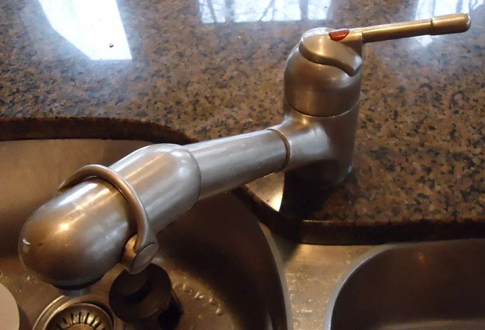 Chrome kitchen faucet at a sink, representing home drinking-water treatment choices