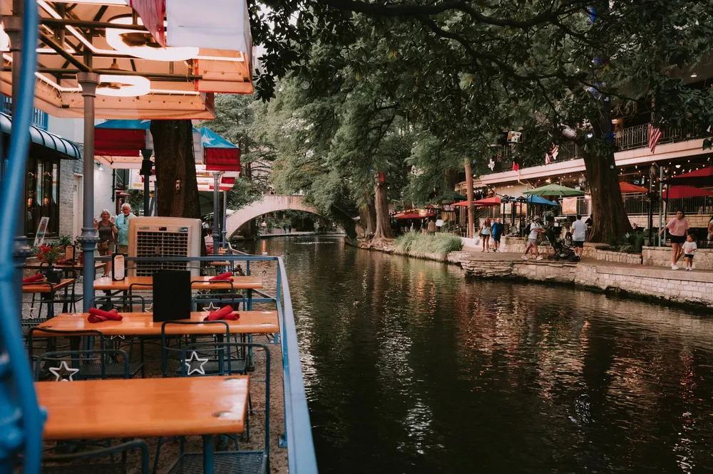 San Antonio River Walk with cafe tables beside the river under cypress trees