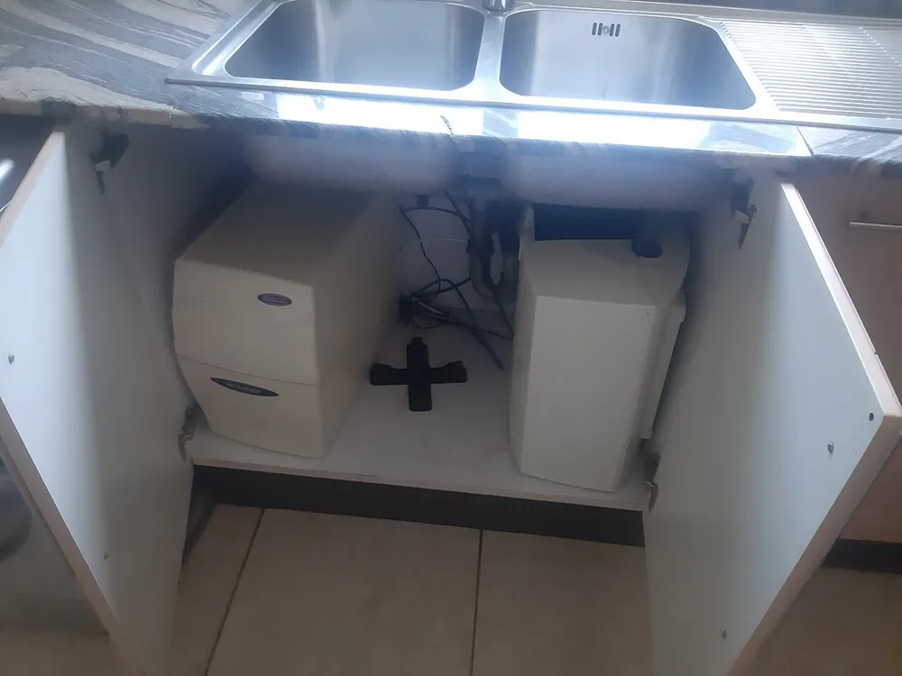 Under-sink water filter system with cartridges and tubing installed in a kitchen cabinet